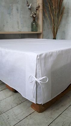 a white table cloth with a bow tied around the edge on a wooden stand in front of a wall