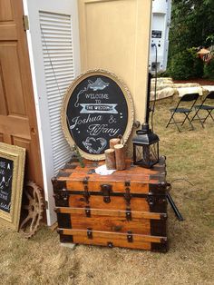 an old trunk sitting next to a chalkboard sign