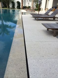 an empty swimming pool with lounge chairs and palm trees in the backgrouds