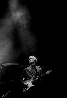 a man that is playing a guitar in the dark