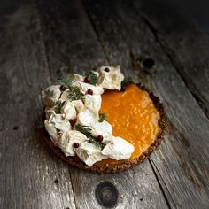 a piece of pie with whipped cream and sprigs on top sitting on a wooden table