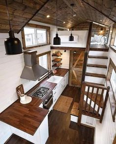 the interior of a tiny house with wood flooring and stairs leading up to the loft