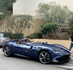 a man standing next to a blue sports car