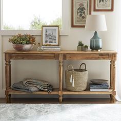 a wooden table with baskets on it next to a lamp and pictures hanging on the wall