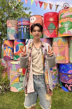 a young man standing in front of stacks of paper hats and giving the peace sign