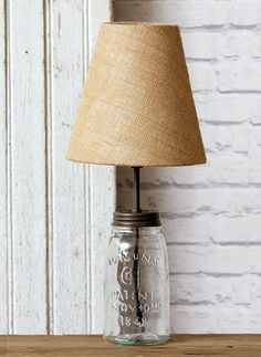 a lamp that is sitting on top of a wooden table next to a white brick wall