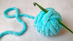 a crocheted ball of yarn sitting on top of a white blanket next to a knitting needle