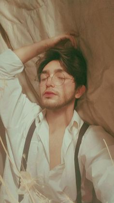 a man with glasses and suspenders is laying down