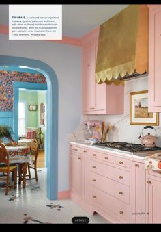 a kitchen with pink cabinets and gold trim around the stove top, along with an arched doorway leading to another room