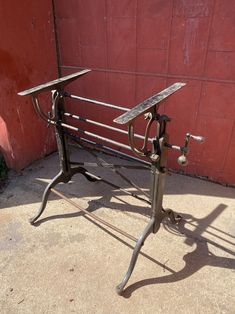 an old metal bench sitting in front of a red wall