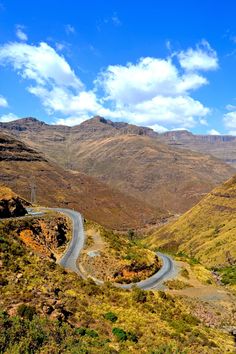 a winding road in the mountains on a sunny day