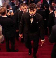 a man in a tuxedo walks down the stairs at an oscars event