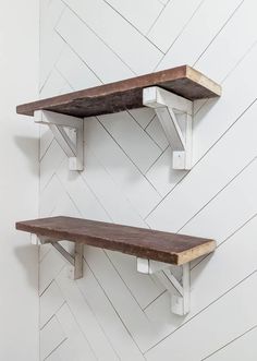 two wooden shelfs on the wall with white chevron walls behind them and wood shelves below