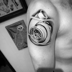 a black and white photo of a man's arm with a wheel tattoo on it