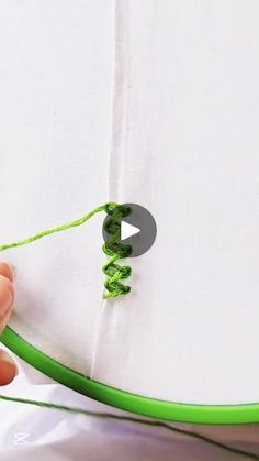 someone is stitching green thread on a piece of paper