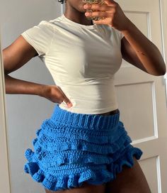 a woman is taking a selfie with her cell phone while wearing a blue crochet skirt