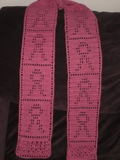 a pink crocheted scarf sitting on top of a couch