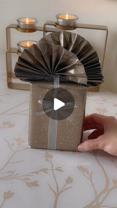 a person holding a gift box with candles in the background