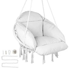 a white hanging chair with tassels and chains on the bottom, next to it's contents