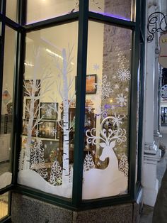 a store front window decorated with paper cut trees and snowflakes on the windows