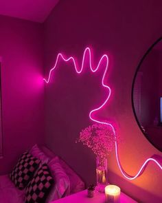 a living room with pink lighting and a large mirror on the wall, next to a couch