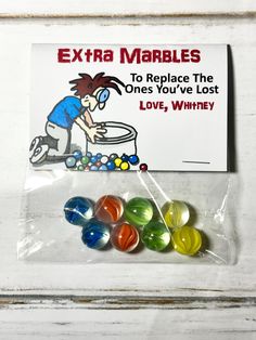 a bag with some candy in it on top of a white table next to a sign that says extra marbles