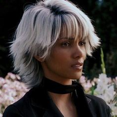 a woman with blonde hair and black shirt in front of flowers looking off to the side