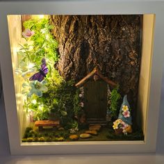 a miniature fairy garden is displayed in a glass case with flowers and trees surrounding it