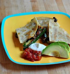 a yellow and blue plate topped with quesadillas, salsa and an avocado