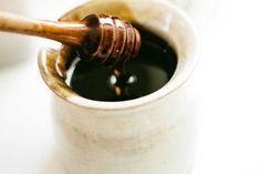 a wooden stick sticking out of a cup filled with black liquid on top of a white table