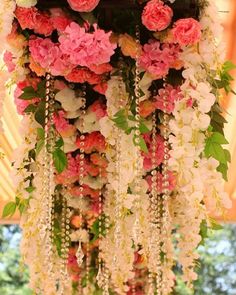 an arrangement of flowers hanging from the ceiling at a wedding or reception in pink and white colors