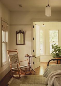 a bedroom with a rocking chair next to a bed and a small potted plant