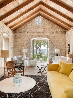 a living room filled with lots of furniture and a stone wall covered in wood beams