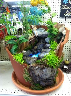 a potted planter filled with lots of plants and rocks in the shape of a waterfall