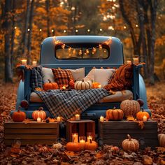 an old truck with pumpkins and candles on the bed is surrounded by fall leaves