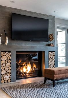 a living room with a fire place and television above the fireplace is decorated in wood logs