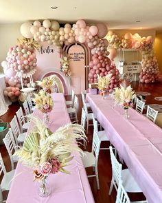 the tables are set up with pink and white tablecloths, flowers, and balloons