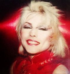 an old photo of a woman with blonde hair and red dress posing for the camera