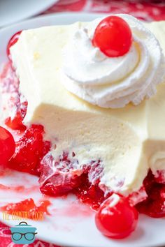 a piece of cheesecake topped with whipped cream and cherries on a white plate