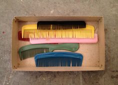 three different colored combs sitting in a box on the floor next to each other