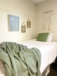 a bed with green blankets and pictures on the wall