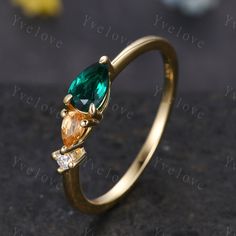 two pear shaped green and yellow gems on a gold ring