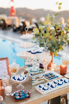 a table topped with cupcakes and cakes next to a pool