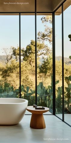 a bath tub sitting in front of a window next to a table with a bowl on it