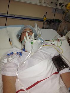 a woman laying in a hospital bed with an oxygen tube attached to her arm and head