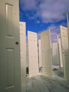 several white doors are opened in front of a blue sky