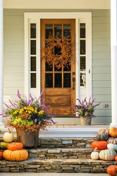 a front porch with pumpkins and flowers on the steps