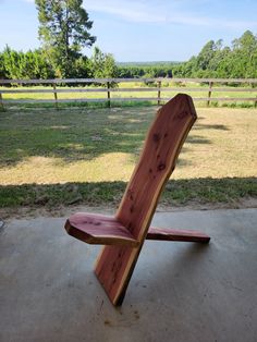 a wooden bench sitting on top of a cement floor next to a lush green field