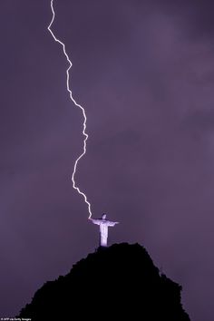 lightning strikes behind the statue of christ on top of a mountain