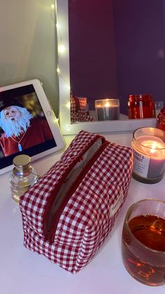 a tablet on a table next to a red and white checkered bag with a candle in front of it